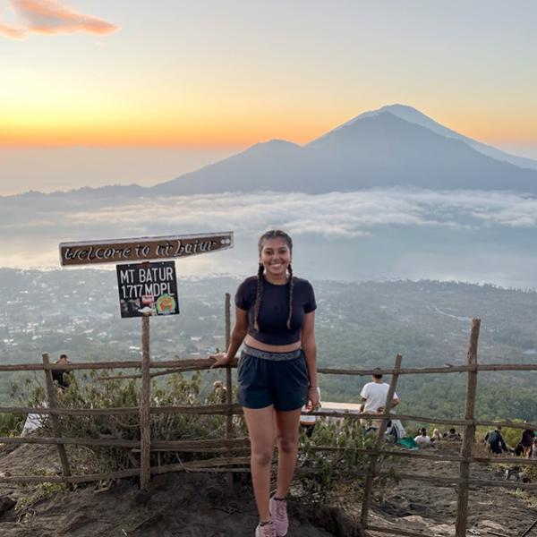 Student poses with sunrise and mountains in the background